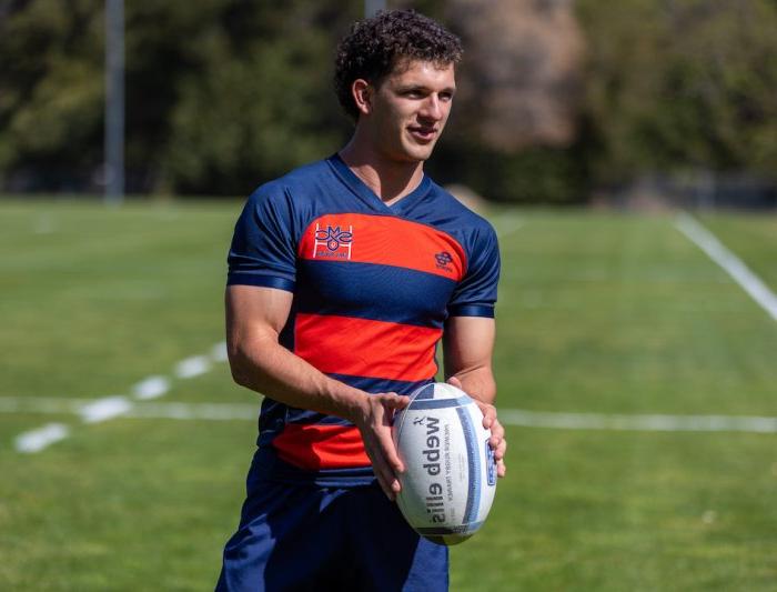 A men's rugby player is holding a ball