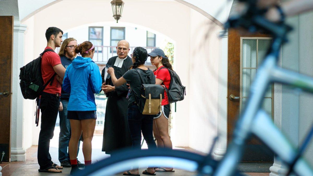 brother speaking with students in hallway with bike in foreground